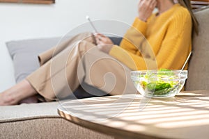 Beautiful Asian woman eats salad with a wide smile, happy smiling face and surfs the internet with laptop computer