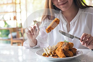 A beautiful asian woman enjoy eating french fries and fried chicken in restaurant