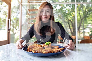 A beautiful asian woman enjoy eating fried chicken and french fries in restaurant