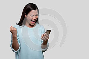 Beautiful asian woman excited and happy, celebrating winning achievement with cellphone in hand, good news, for advertisement with