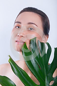 Beautiful asian woman face portrait with green leaf . Concept for skin care or organic cosmetics