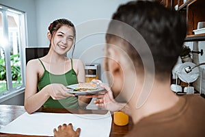 beautiful asian woman feeding her partner in the dining room