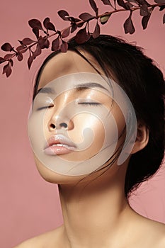 Beautiful asian woman with fresh daily makeup. Vietnamese beauty girl in spa treatment with green leafs near face