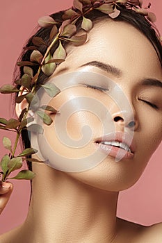 Beautiful asian woman with fresh daily makeup. Vietnamese beauty girl in spa treatment with green leafs near face