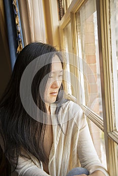 Beautiful Asian Woman gazes out a City Window