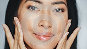 Beautiful Asian Woman Gently Touching Her Face, Looking at Camera. Young Adult Female with Lush Bl