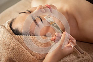 Beautiful Asian Woman getting facial nourishing at spa salon.