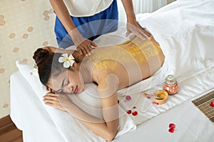 Beautiful Asian woman having exfoliation treatment with body scrub in spa salon, scrubbing and skin care concept, enjoying and