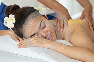 Beautiful Asian woman having exfoliation treatment with body scrub in spa salon, scrubbing and skin care concept, enjoying and