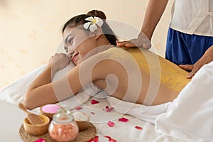 Beautiful Asian woman having exfoliation treatment with body scrub in spa salon, scrubbing and skin care concept, enjoying and