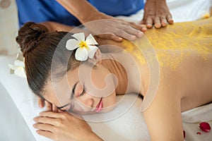 Beautiful Asian woman having exfoliation treatment with body scrub in spa salon, scrubbing and skin care concept, enjoying and