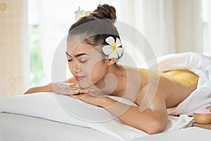 Beautiful Asian woman having exfoliation treatment with body scrub in spa salon, scrubbing and skin care concept, enjoying and
