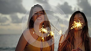 Beautiful asian woman and her friends are having fun playing sparklers on the beach during Twilight.