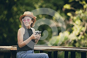 beautiful asian woman holdin smart phone and cup of coffee sitting at home terrace