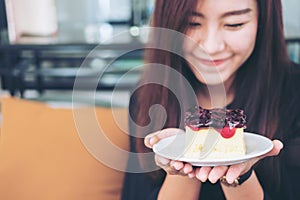 A beautiful asian woman holding blueberry cheese cake with feeling happy and good lifestyle