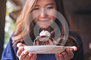 A beautiful asian woman holding chocolate cake roll and whipped cream with feeling happy and good lifestyle