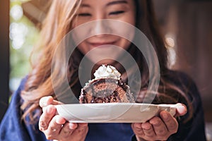 A beautiful asian woman holding chocolate cake roll and whipped cream with feeling happy and good lifestyle