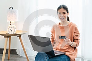 Beautiful Asian woman holding credit card and using digital laptopà¹ƒ