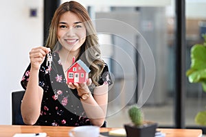 Beautiful woman holding house model and house key in hand. Insurance or loan real estate concept.