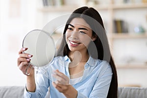 Beautiful Asian Woman Holding Magnifying Mirror At Home, Looking At Her Reflection