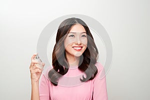 Beautiful asian woman holding a perfume bottle and applying it