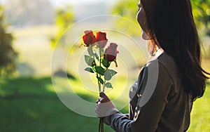 A beautiful asian woman holding red roses flower in the park