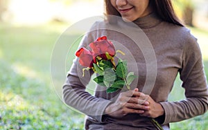 A beautiful asian woman holding red roses flower in the park