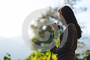 A beautiful asian woman holding red roses flower in the park