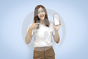 Beautiful asian woman holding and showing blank screen smart phone isolated on blue background. with clipping paths