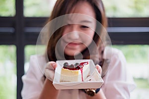A beautiful Asian woman holding and showing blueberry cheese cake with feeling happy and good lifestyle
