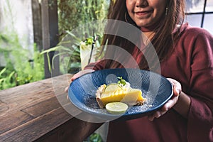 A beautiful asian woman holding and showing a yellow lemon curd cake with feeling happy and good lifestyle