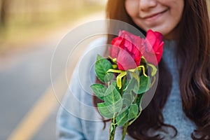 A beautiful asian woman holding and smelling red roses flower with feeling happy on Valentine`s day