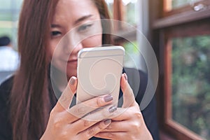 A beautiful Asian woman holding , using and looking at smart phone with feeling happy