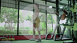 Beautiful Asian woman is lifting a steel ball in the gym to strengthen her muscle mass.