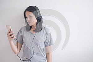 Beautiful Asian woman listening music with headphone and smartphone on a white background with copy space.