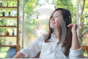 A beautiful asian woman listening to music with headphone in cafe with feeling relax