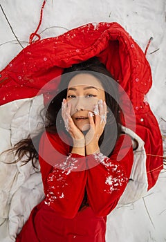 Beautiful asian woman in long red dress near the reeds over winter background. Fairy tale girl on winter landscape.