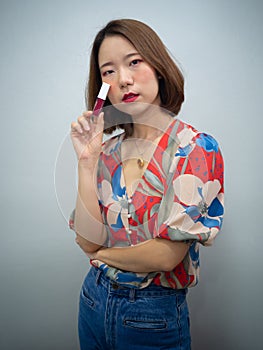 Beautiful Asian woman after makeup smile and show three in one lipstick create over lips , eyeshadow and blush onestop in cosmetic