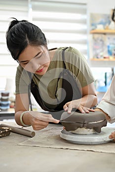 A beautiful Asian woman making moulding clay plate, making a ceramic plate