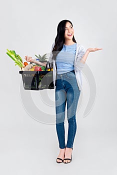 Beautiful Asian woman with open hand holding supermarket shopping basket