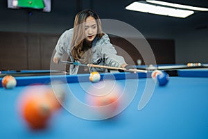 beautiful asian woman poking the biliiard ball