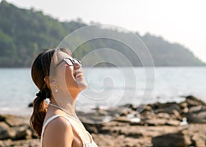 Beautiful Asian woman portrait with sunglasses on the beach in summer vibes.