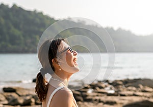 Beautiful Asian woman portrait with sunglasses on the beach in summer vibes.