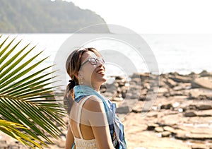 Beautiful Asian woman portrait with sunglasses on the beach in summer vibes.