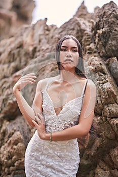 Beautiful asian woman posing on a beach with rocks