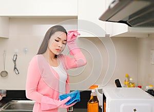 Beautiful asian woman in protective gloves cleaning kitchen cabinet