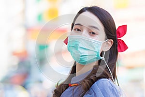 A beautiful Asian woman in a Qipao dress standing smiling happily, her face wearing a mask to protect against viruses and