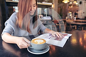 A beautiful asian woman reading magazine while drinking coffee in modern cafe