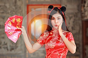 Beautiful Asian woman in red Chinese dress traditional cheongsam qipao with gesture of showing red envelope or Any Pao with