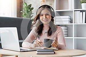 Beautiful asian woman relaxing using laptop computer while sitting on table with coffee, concept at home